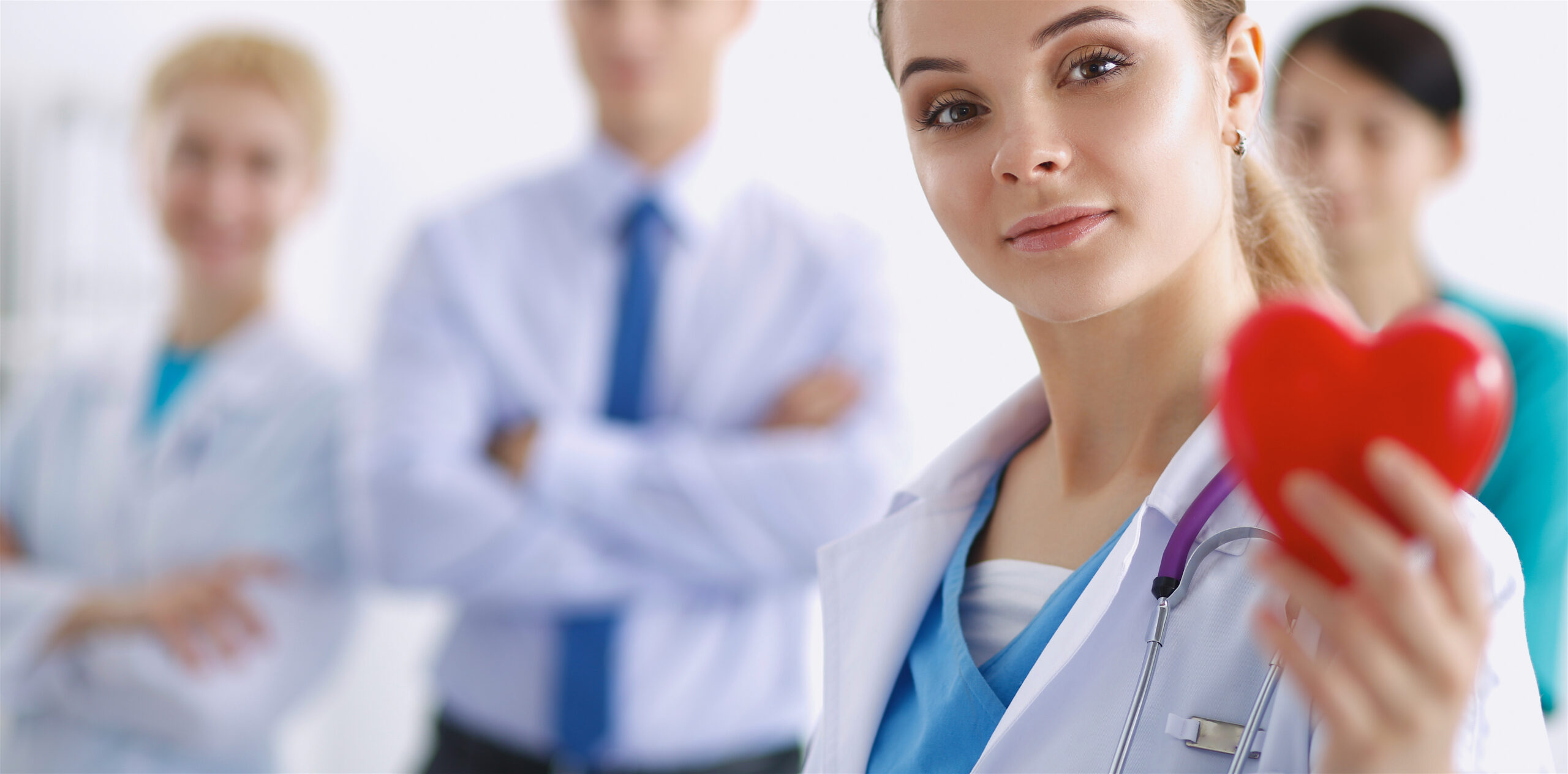 Female clinician holding a red heart with three colleagues in the background